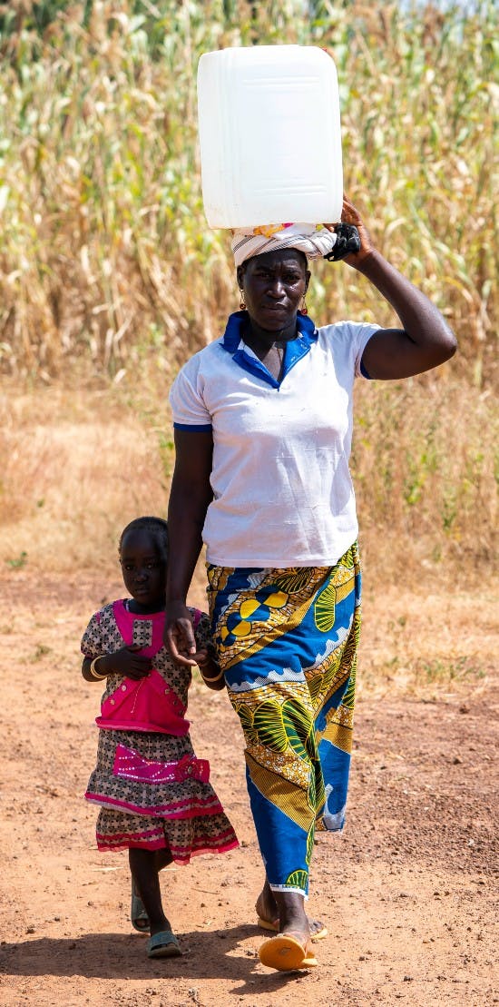 Kvinde og lille barn henter vand ved brønden i Burkina Faso