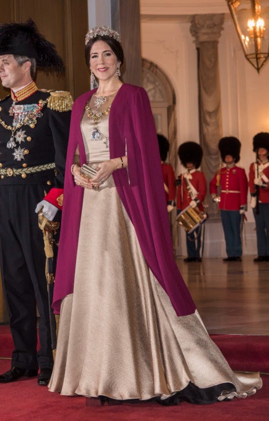 Kronprinsesse Mary i en gylden gallakjole af Jesper Høvring og den blommefarvede kappe af Lasse Spangenberg.&nbsp;&nbsp;
