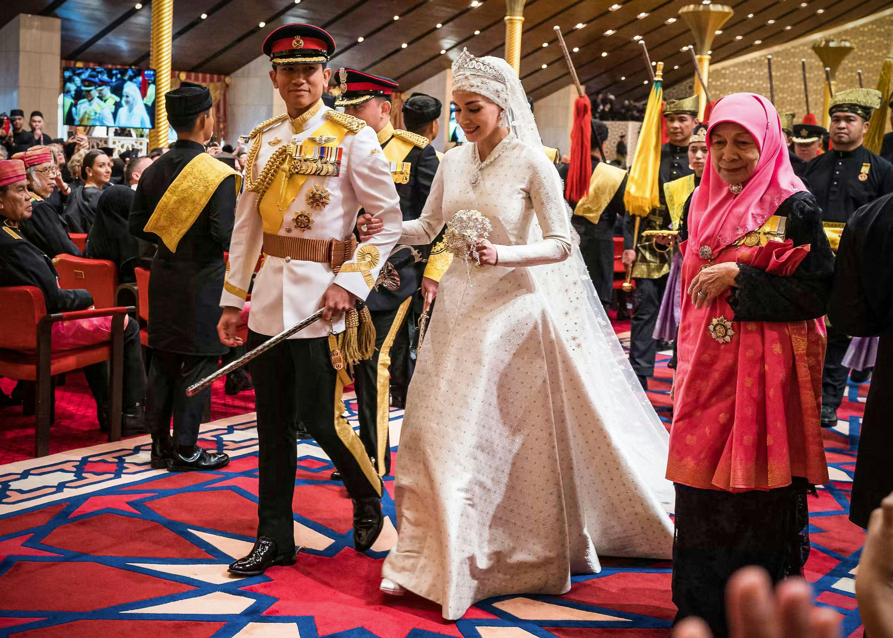 Prince Abdul Mateen (L) and Yang Mulia Anisha Rosnah walk down the aisle during their wedding reception at Istana Nurul Iman in Brunei's capital Bandar Seri Begawan on January 14, 2024. Lavish celebrations for the wedding of Brunei's Prince Abdul Mateen and his wife reached a climax on January 14 with a glittering ceremony attended by government leaders and blue-blooded guests from Asia and the Middle East. (Photo by IQBAL SELAMAT / AFP)