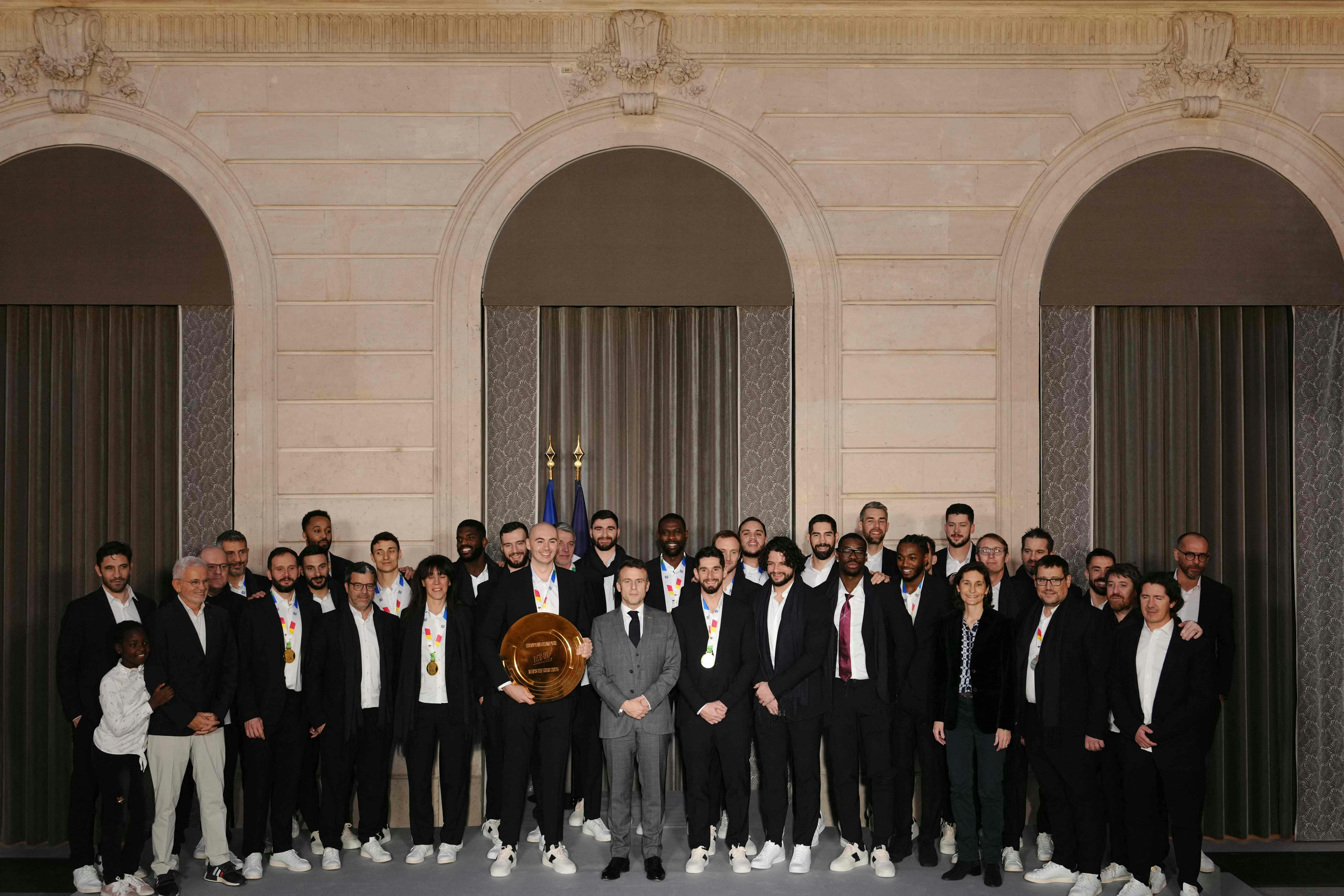 French President Emmanuel Macron (C) poses with France's handball team at the Elysee Palace in Paris on January 29, 2024 after their victory over Denmark to win the Men's EURO 2024 EHF Handball European Championship. (Photo by Dimitar DILKOFF / AFP)
