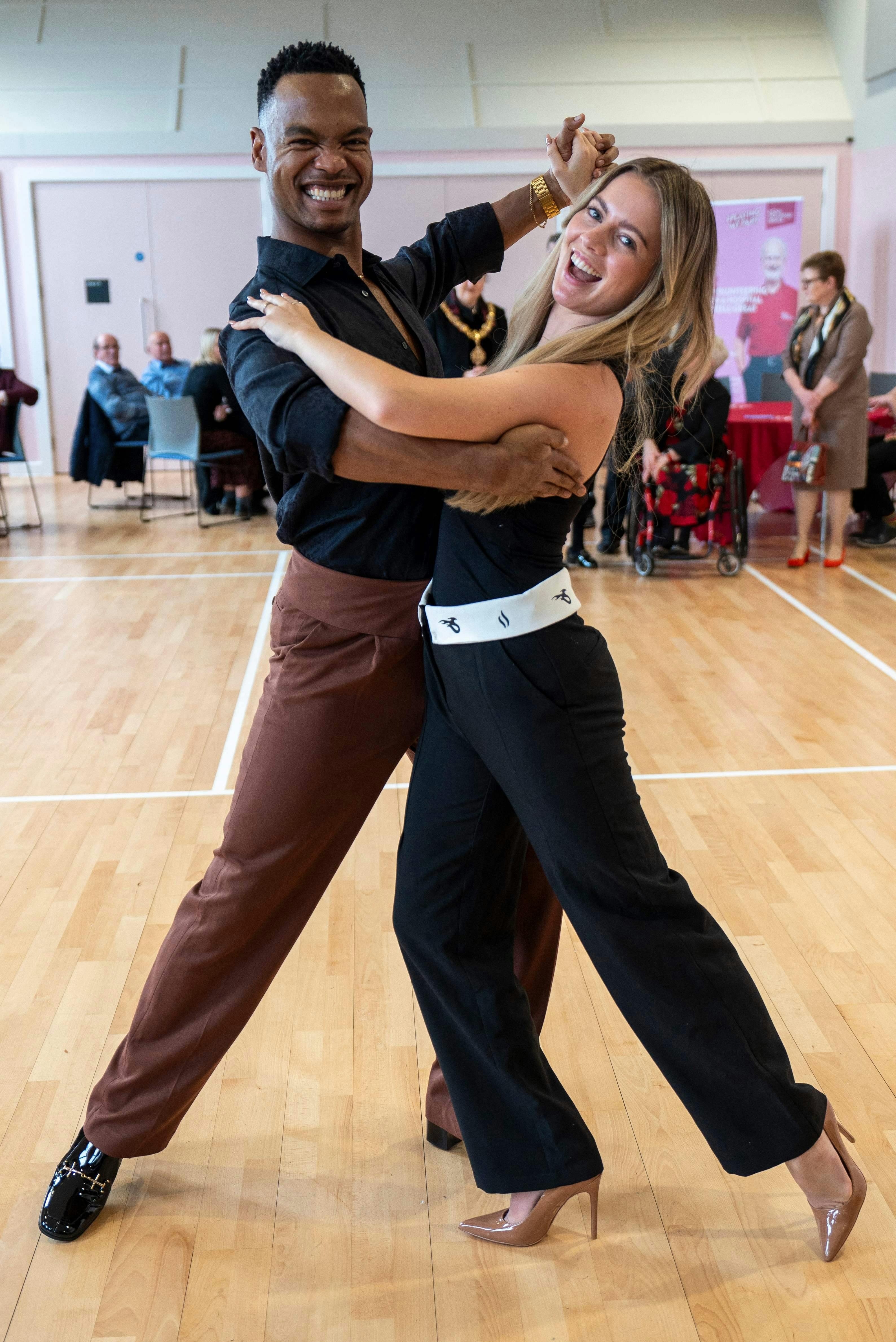 Dancer Johannes Radebe (L), a star on Strictly come Dancing and dancer Tasha Ghouri (R) who stars in Love Island, perform for Britain's Queen Camilla (not pictured) as she visits, in her role as President of the Royal Voluntary Service (RVS), the newly opened Meadows Community Centre in Cambridge, eastern England on February 2, 2024. (Photo by Arthur Edwards / POOL / AFP)