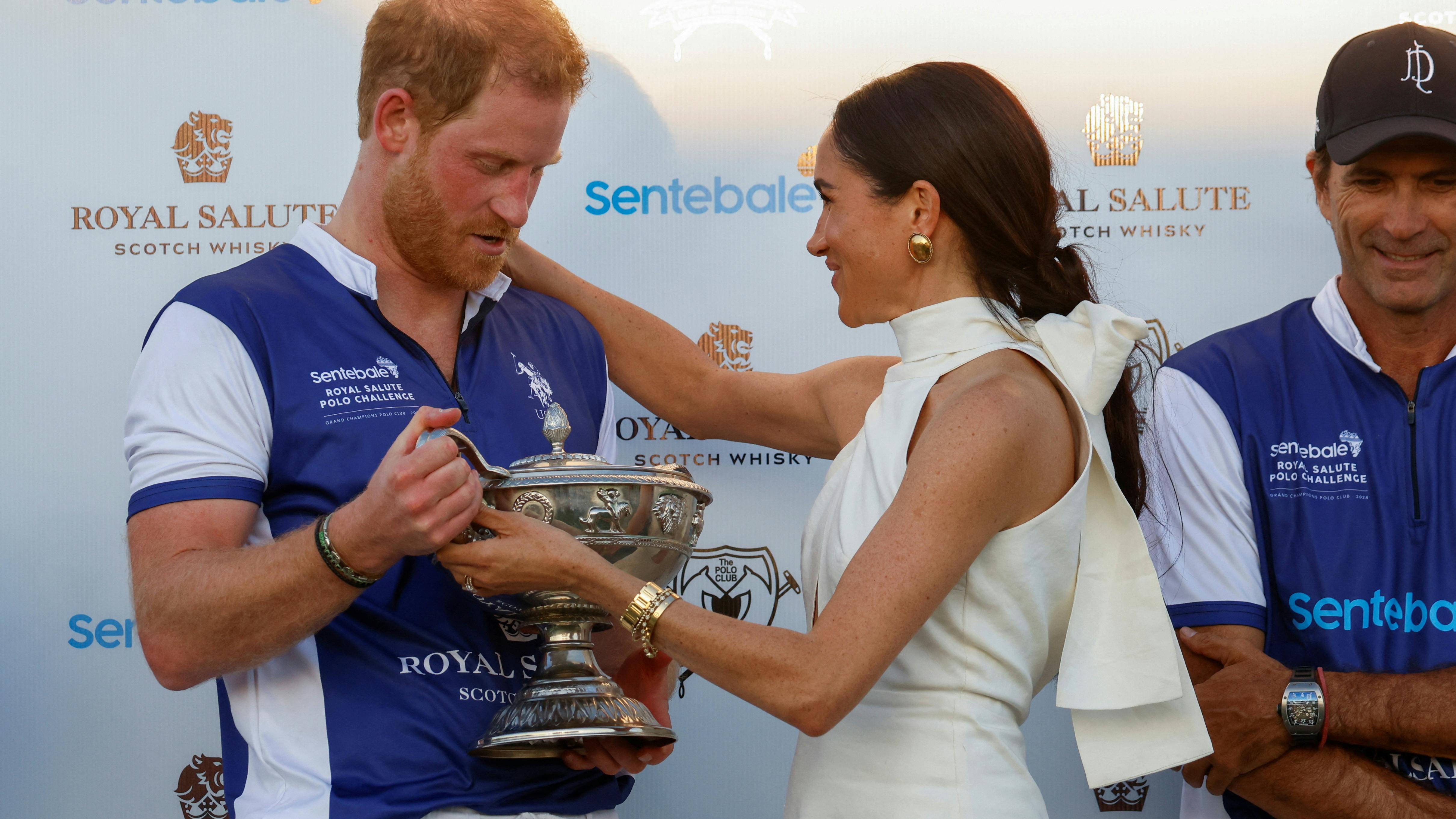 Meghan, Duchess of Sussex, hands a trophy to Britain's Prince Harry following the Royal Salute Polo Challenge to benefit Sentebale, a charity founded by him and Prince Seeiso of Lesotho to support children in Lesotho and Botswana, in Wellington, Florida, U.S., April 12, 2024. REUTERS/Marco Bello