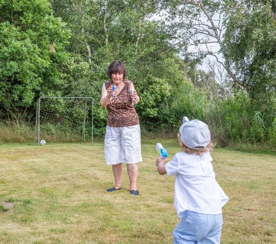 Farmor Mona skyder med vandpistol med barnebarnet Lucas. 