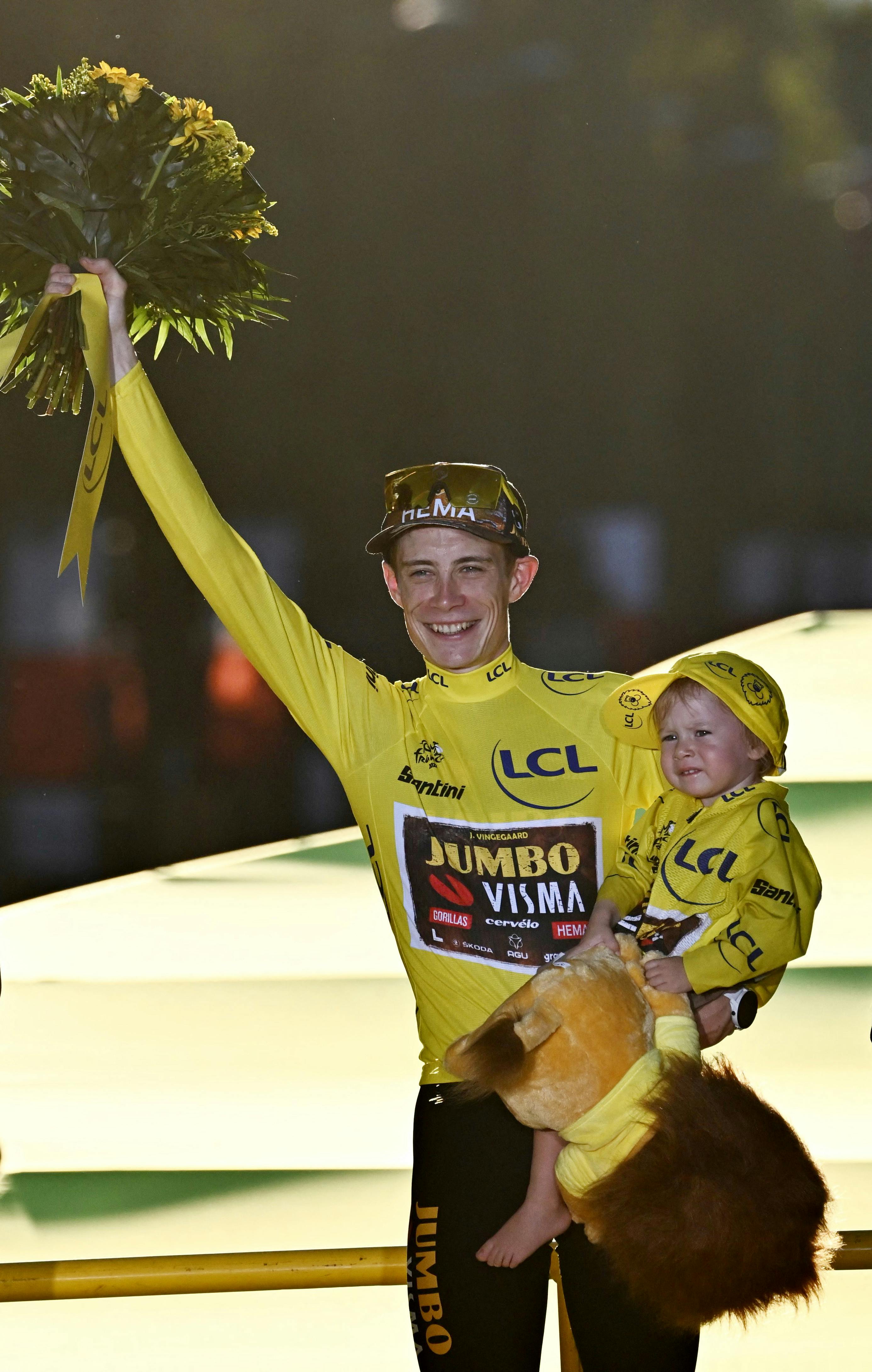 Jumbo-Visma team's Danish rider Jonas Vingegaard holds his daughter Frida as he celebrates on the podium with the overall leader's yellow jersey after winning the 109th edition of the Tour de France cycling race, after the 21st and final 115, 6 km stage between La Defense Arena in Nanterre, outside Paris, and the Champs-Elysees in Paris, France, on July 24, 2022. Anne-Christine POUJOULAT / AFP