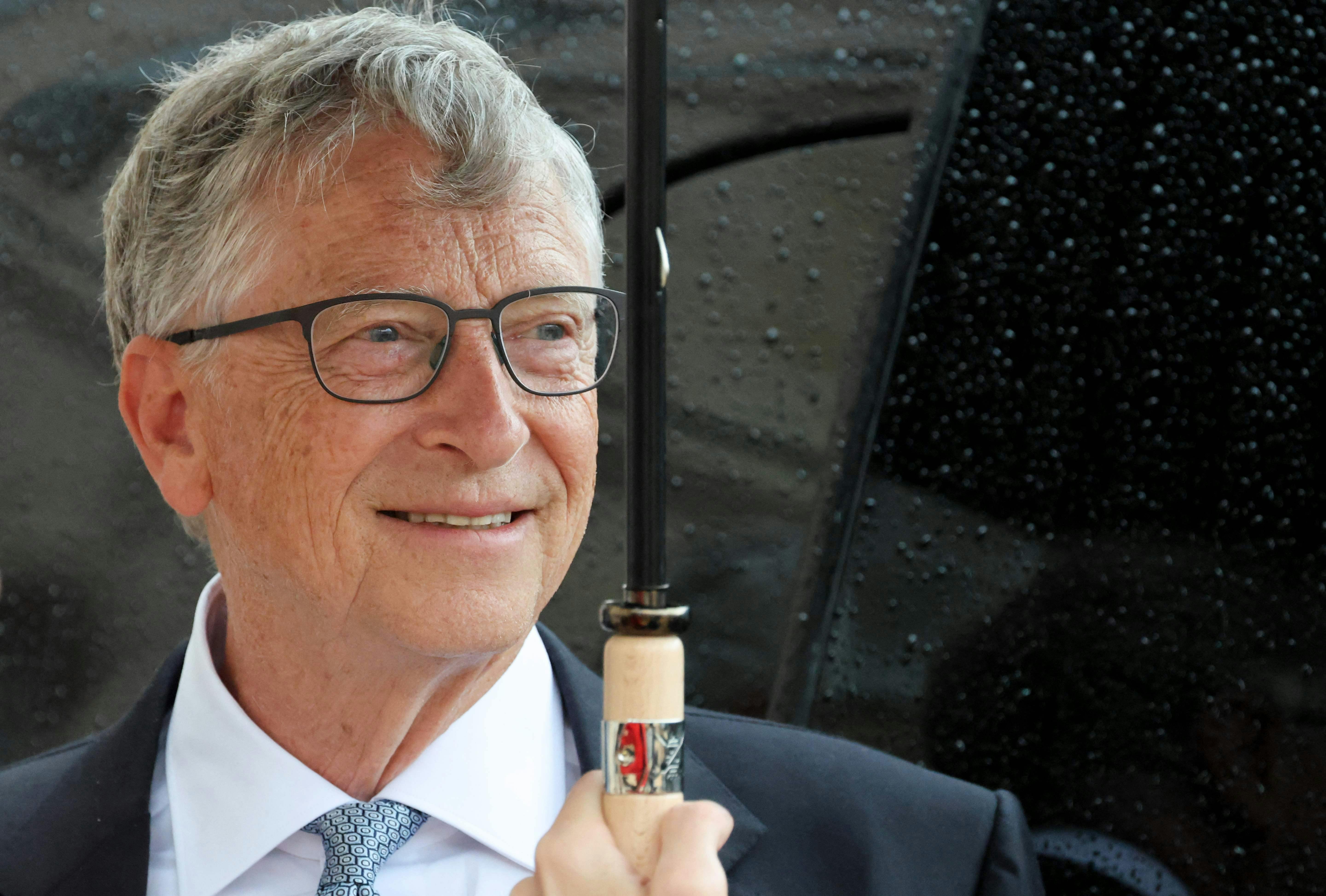 Microsoft founder Bill Gates shelters under an umbrella as he departs after a meeting with France's President at The Elysee Presidential Palace in Paris on July 27, 2024. (Photo by Ludovic MARIN / AFP)