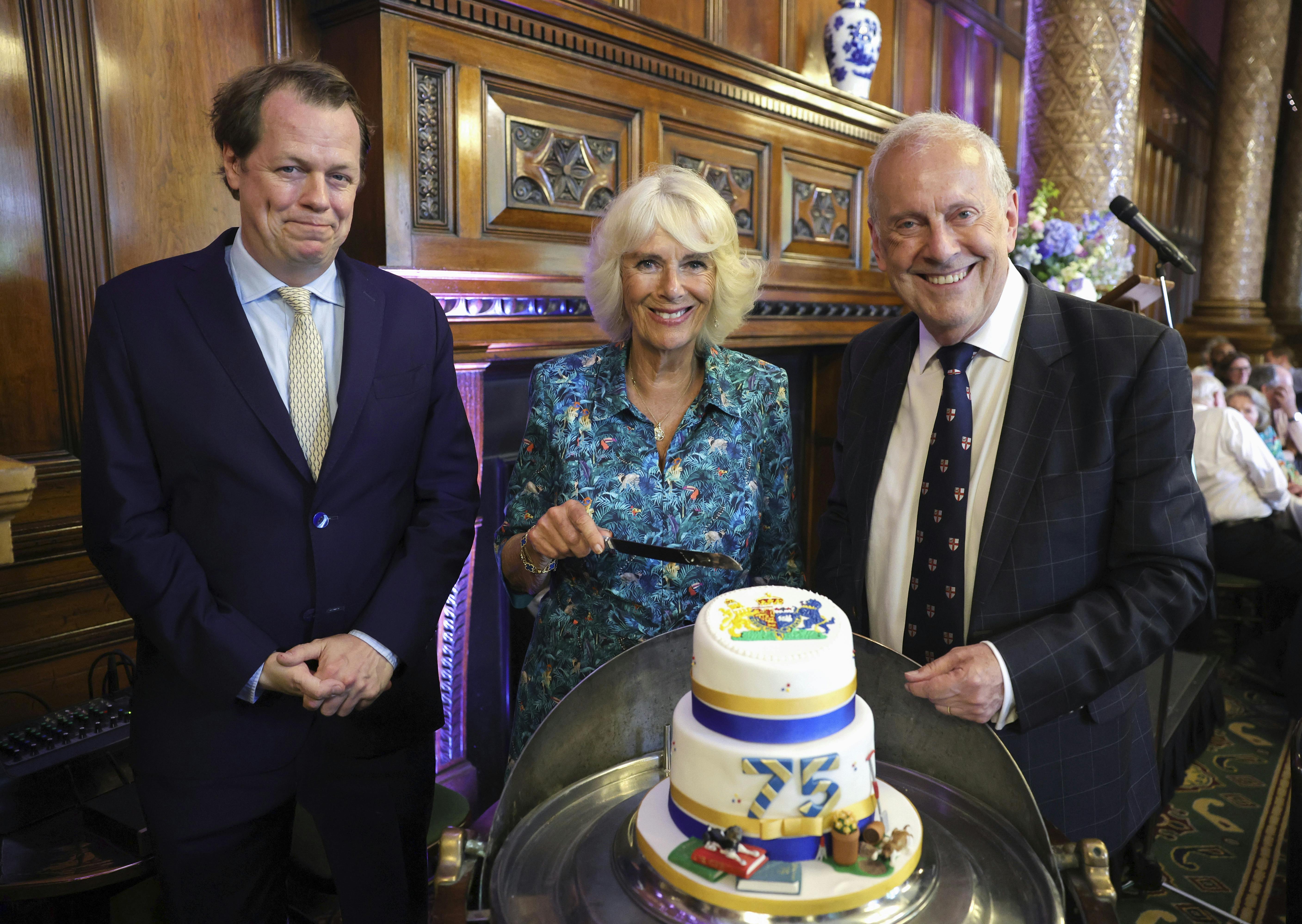 Tom Parker Bowles, left, Camilla, Duchess of Cornwall, and Gyles Brandreth, founder of Poetry Together, right, during The Oldie Luncheon, in celebration of Camilla's 75th Birthday at National Liberal Club in London, Tuesday, July 12, 2022. (Chris Jackson/Pool via AP)