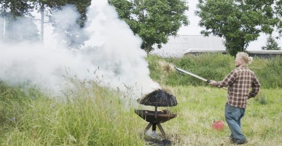 Markus Hvass smider halm på grillen.