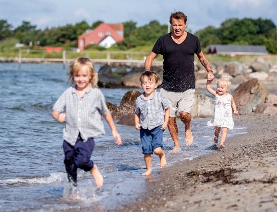 Dennis Knudsen på stranden i Korsør med sine tre børn.