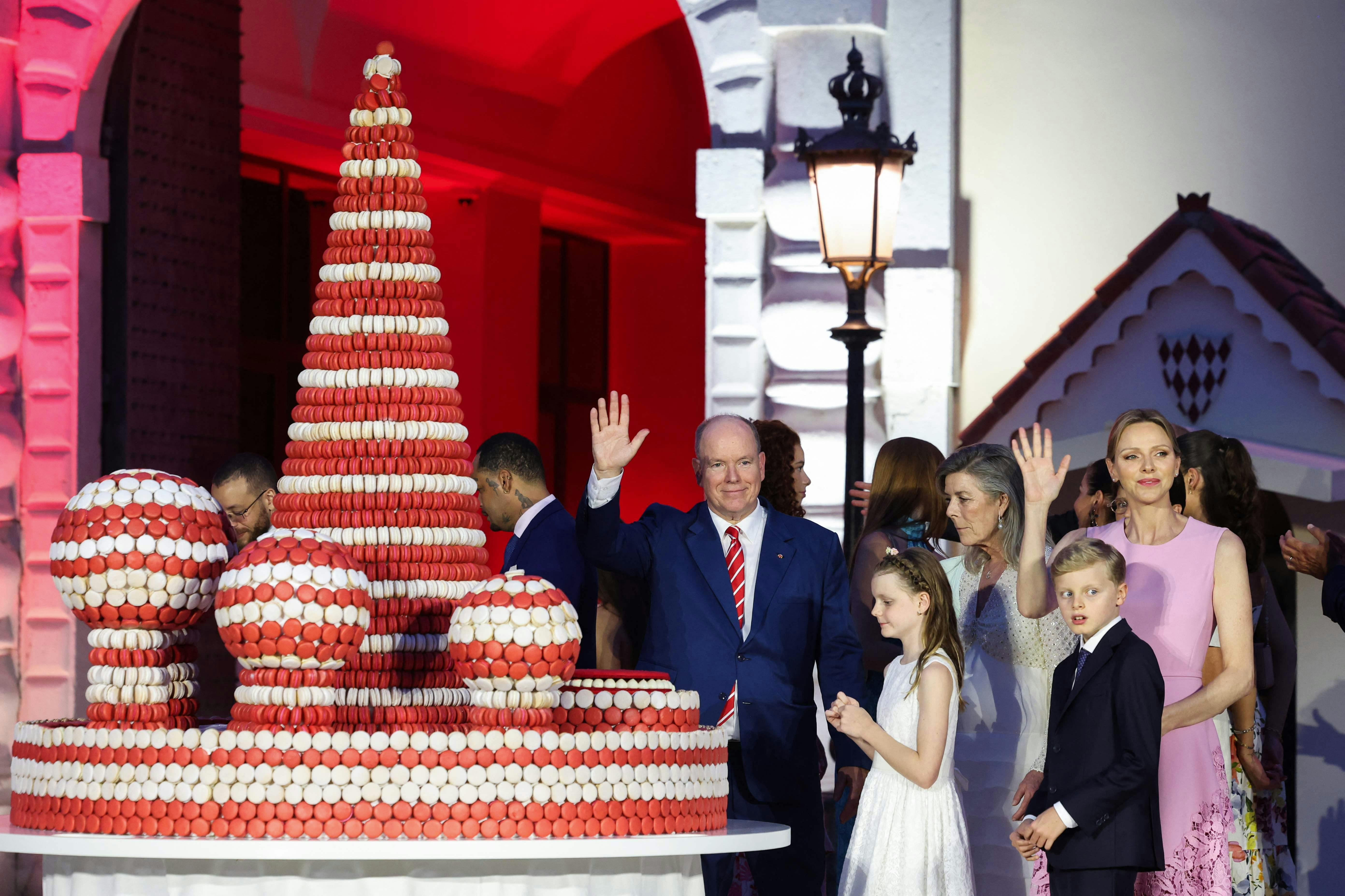 (From C-R) Albert II of Monaco waves after cutting the cake next to daughter and twin to Jacques Gabriella Grimaldi, son and twin to Gabriella Jacques Grimaldi and Charlene of Monaco during the 20th anniversary of the accession of Prince Albert II in Monaco, on July 19, 2025. (Photo by Valery HACHE / AFP) / NO TABLOIDS WEB & PRINT, NO DAILY MAIL, NO DAILY MAIL GROUP (DMGT), NO VOICI, NO CLOSER