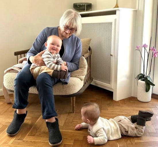 Inge-Lise Kjeldgaard med Nora på skødet, mens Emma kravler på gulvet.