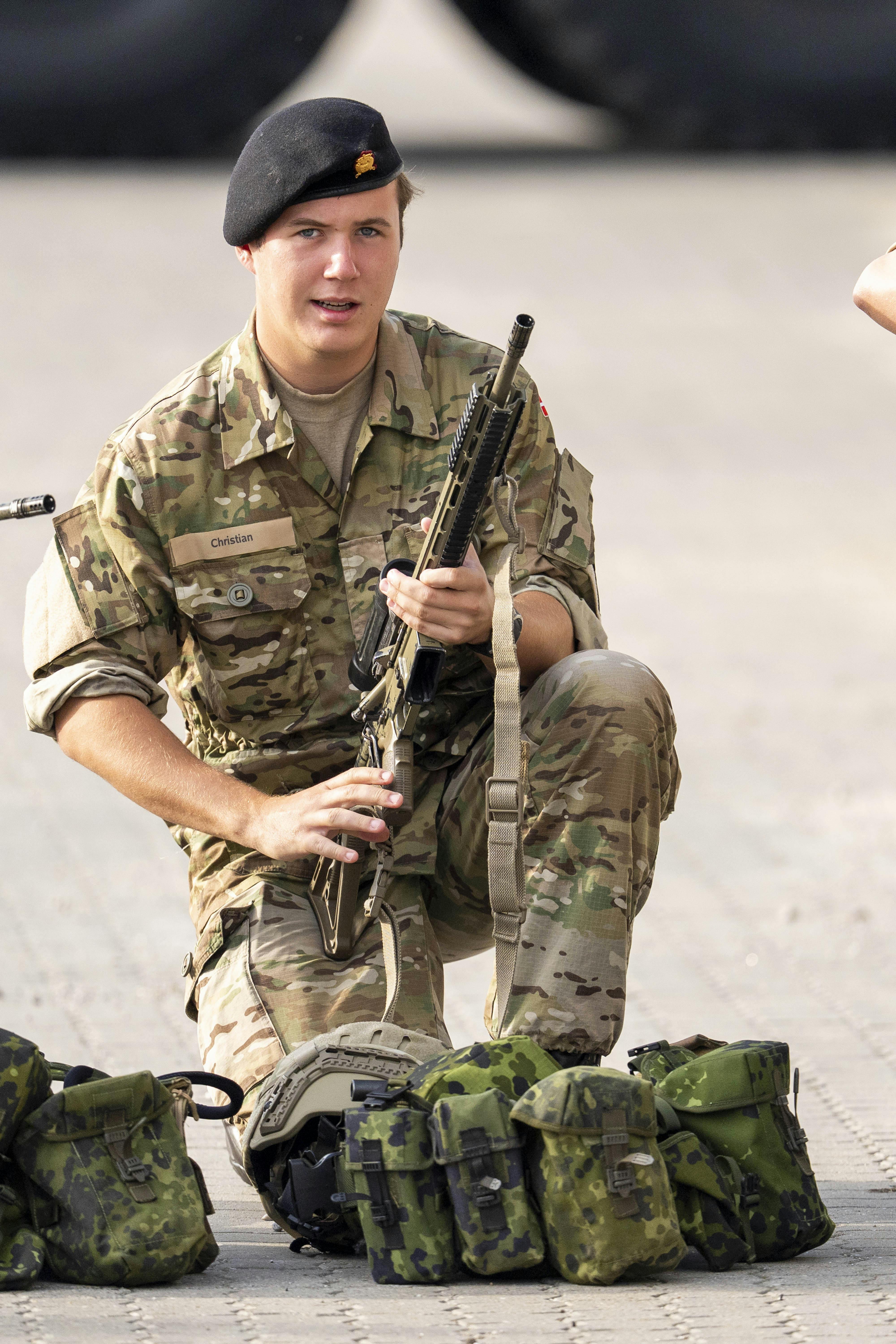 Kronprins Christian i uniform og med et våben på kasernen. 