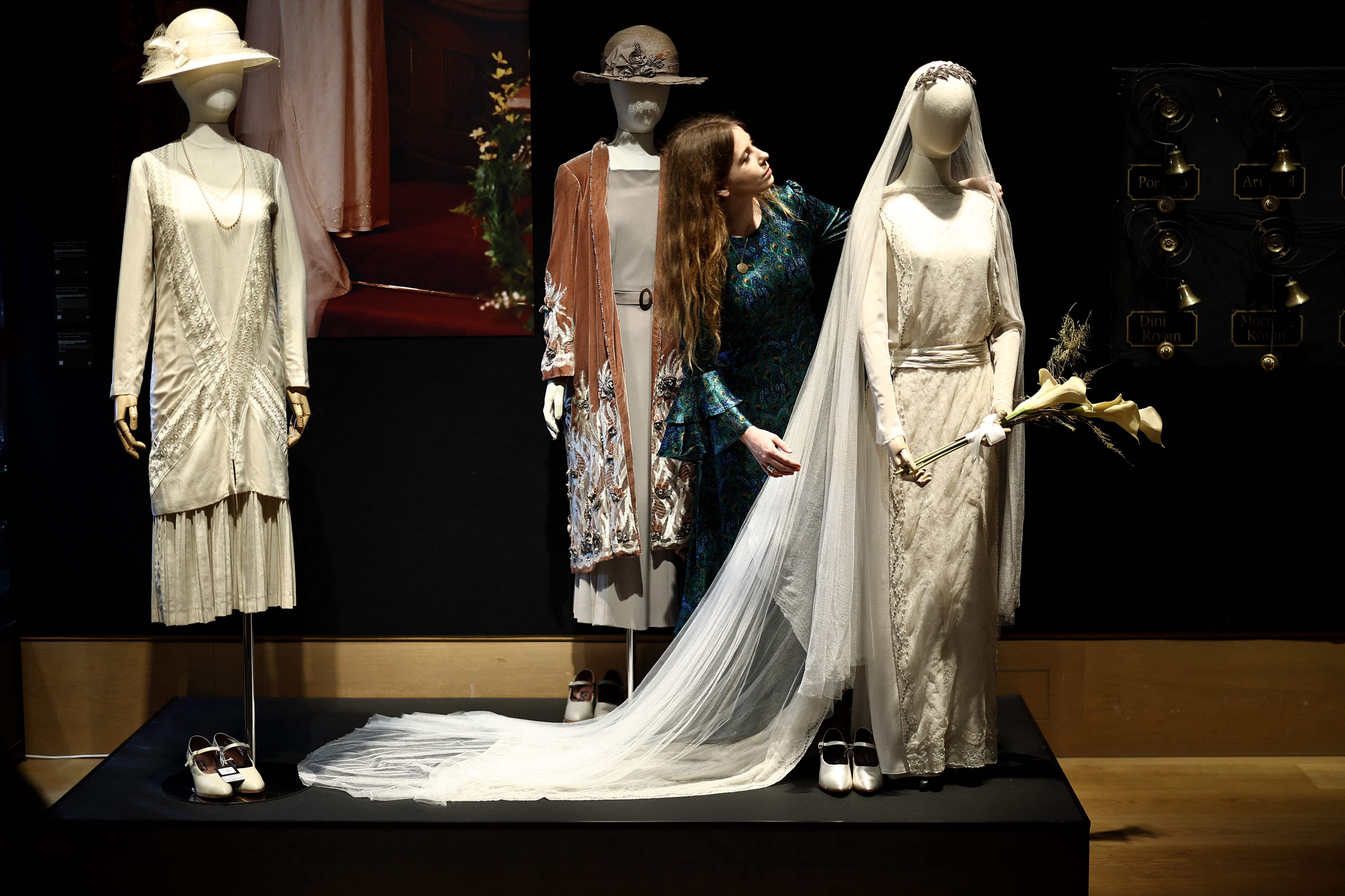 An auction house staff member looks at a wedding dress belonging to the character Lady Mary from the TV and film series Downton Abbey during a press preview for an exhibition of props, costumes and other items from the franchise before they go to auction, in central London on August 8, 2025. (Photo by HENRY NICHOLLS / AFP)