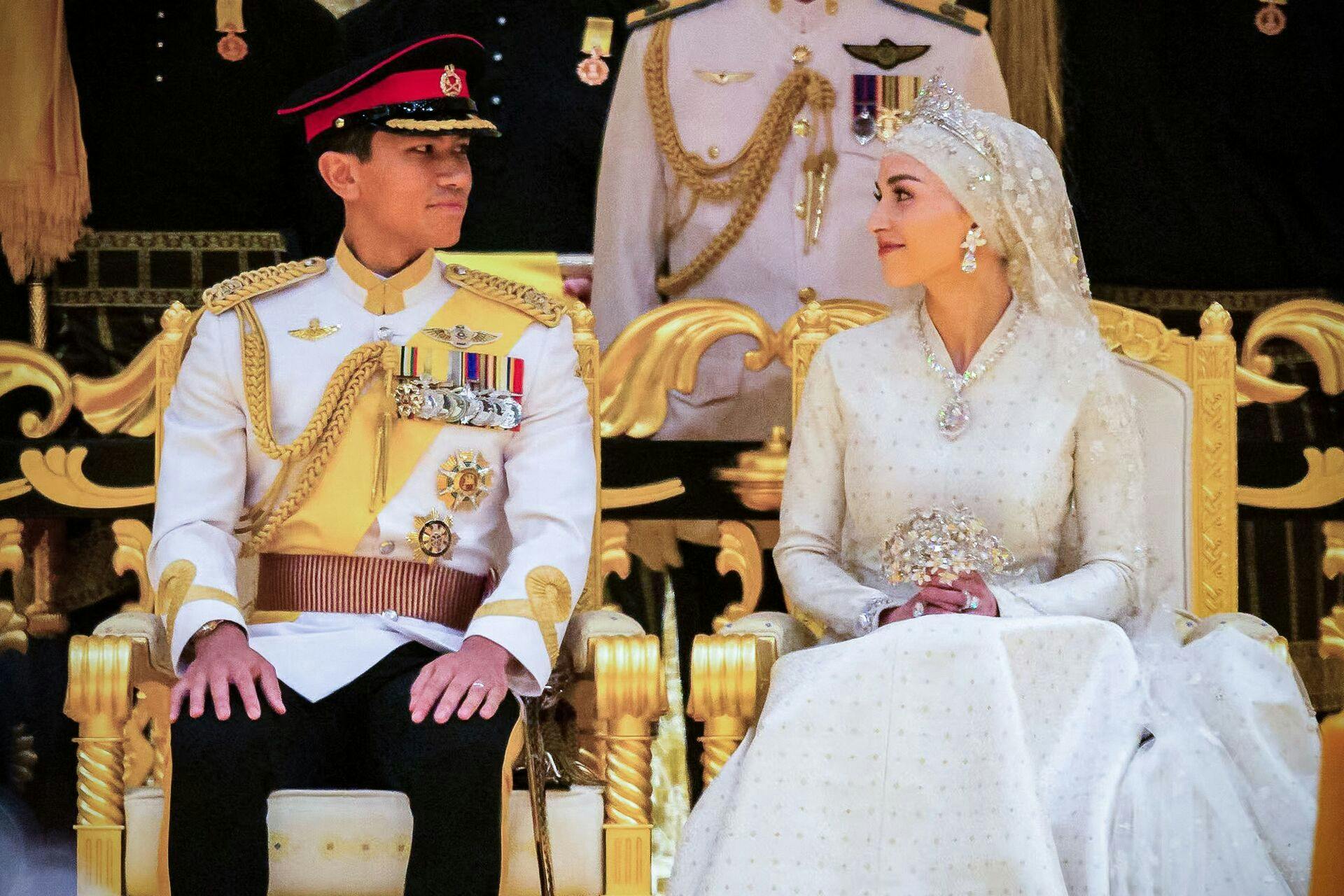 Prince Abdul Mateen (L) and Yang Mulia Anisha Rosnah sit during their wedding reception at Istana Nurul Iman in Brunei's capital Bandar Seri Begawan on January 14, 2024. Lavish celebrations for the wedding of Brunei's Prince Abdul Mateen and his wife reached a climax on January 14 with a glittering ceremony attended by government leaders and blue-blooded guests from Asia and the Middle East. (Photo by IQBAL DATO HJ SELAMAT / AFP)