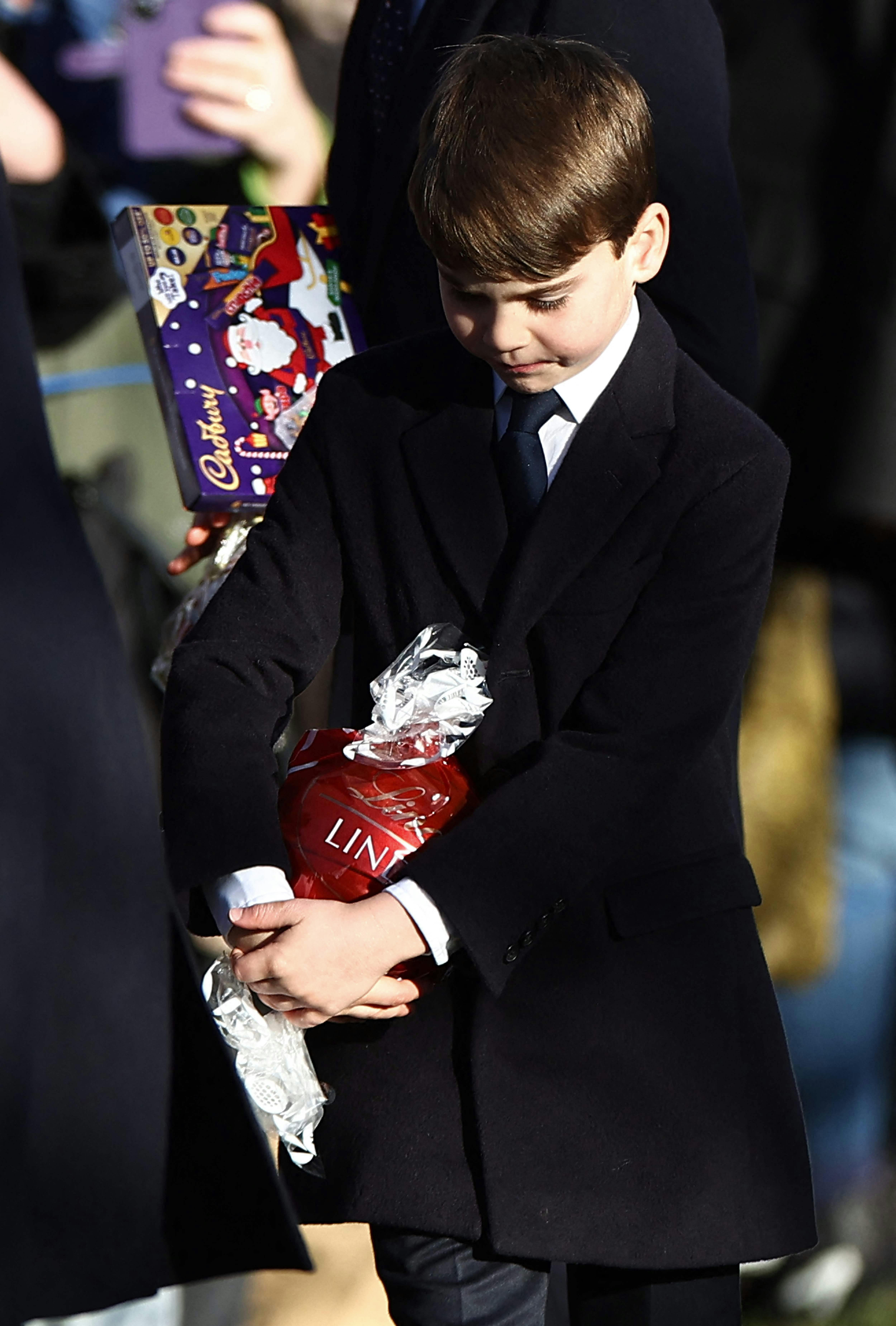 TOPSHOT - Britain's Prince Louis of Wales and Britain's Prince George of Wales hold chocolate received from well-wishers after attending the Royal Family's traditional Christmas Day service at St Mary Magdalene Church on the Sandringham Estate in eastern England, on December 25, 2025. (Photo by Henry NICHOLLS / AFP)