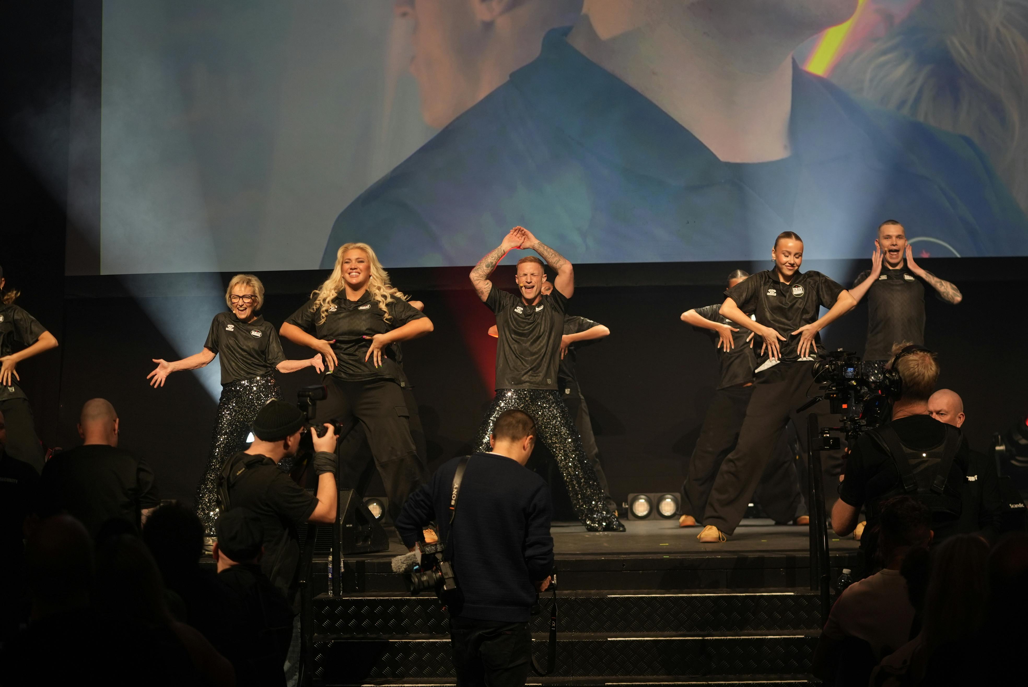 Tine Gøtzsche i en dans på scenen med sine medværter.