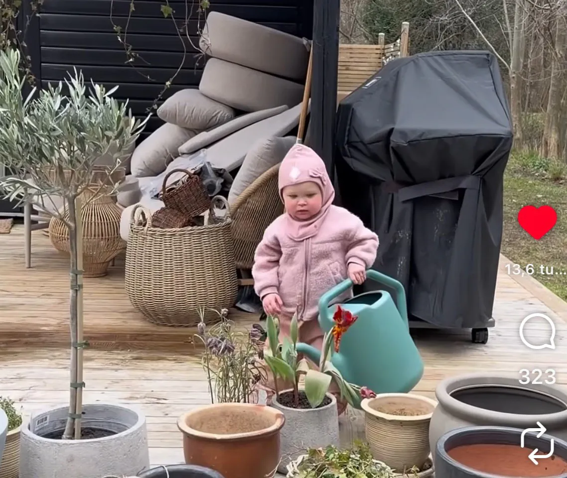 Nora sørger for vand i blomster-krukkerne på terrassen. 