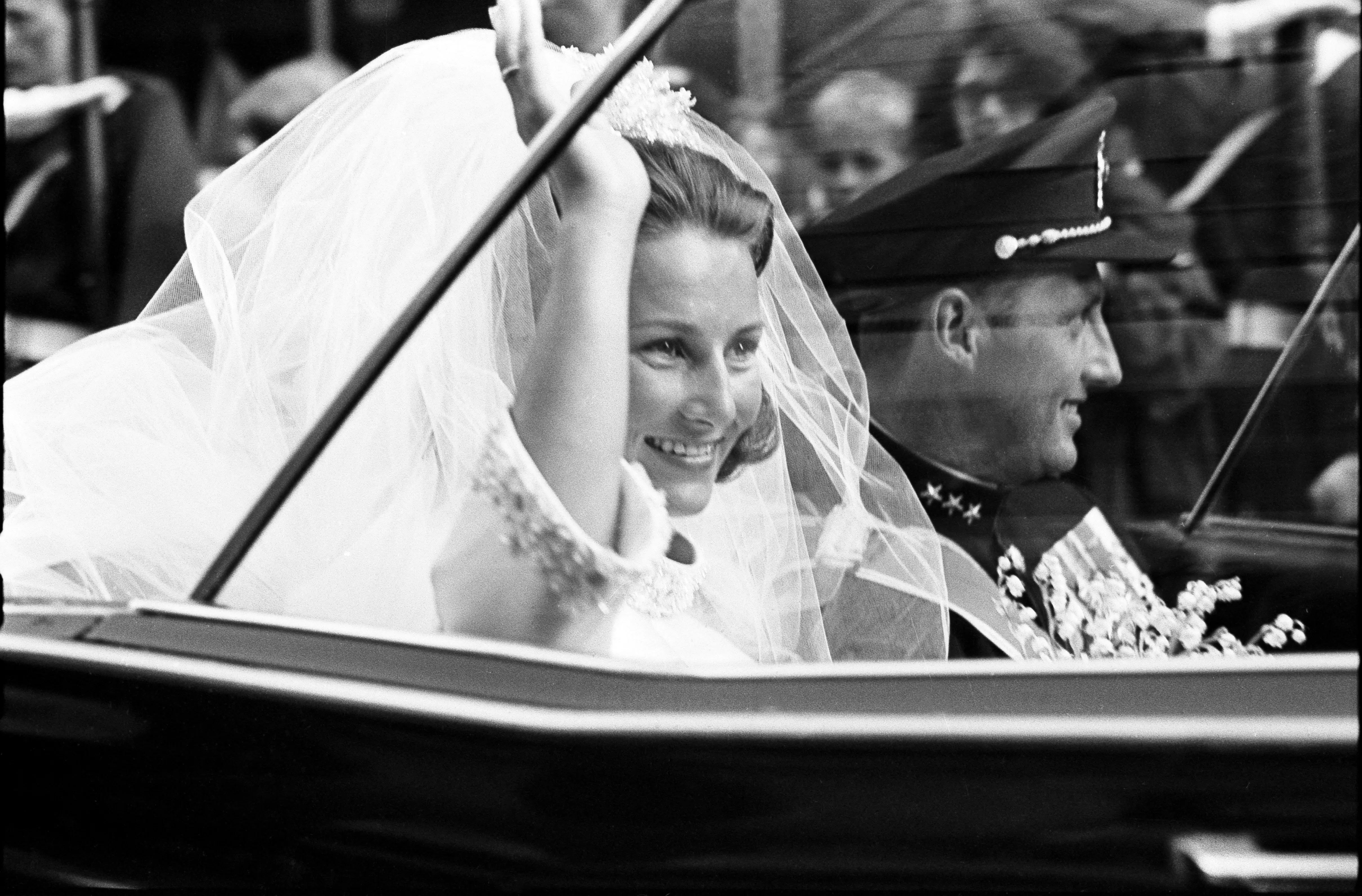A picture taken on August 29, 1968 shows Norway's Crown Prince Harald and Sonja Haraldsen waving as they leave in their car the Oslo Cathedral during their wedding ceremony. Vidar Knai / NTB scanpix / AFP