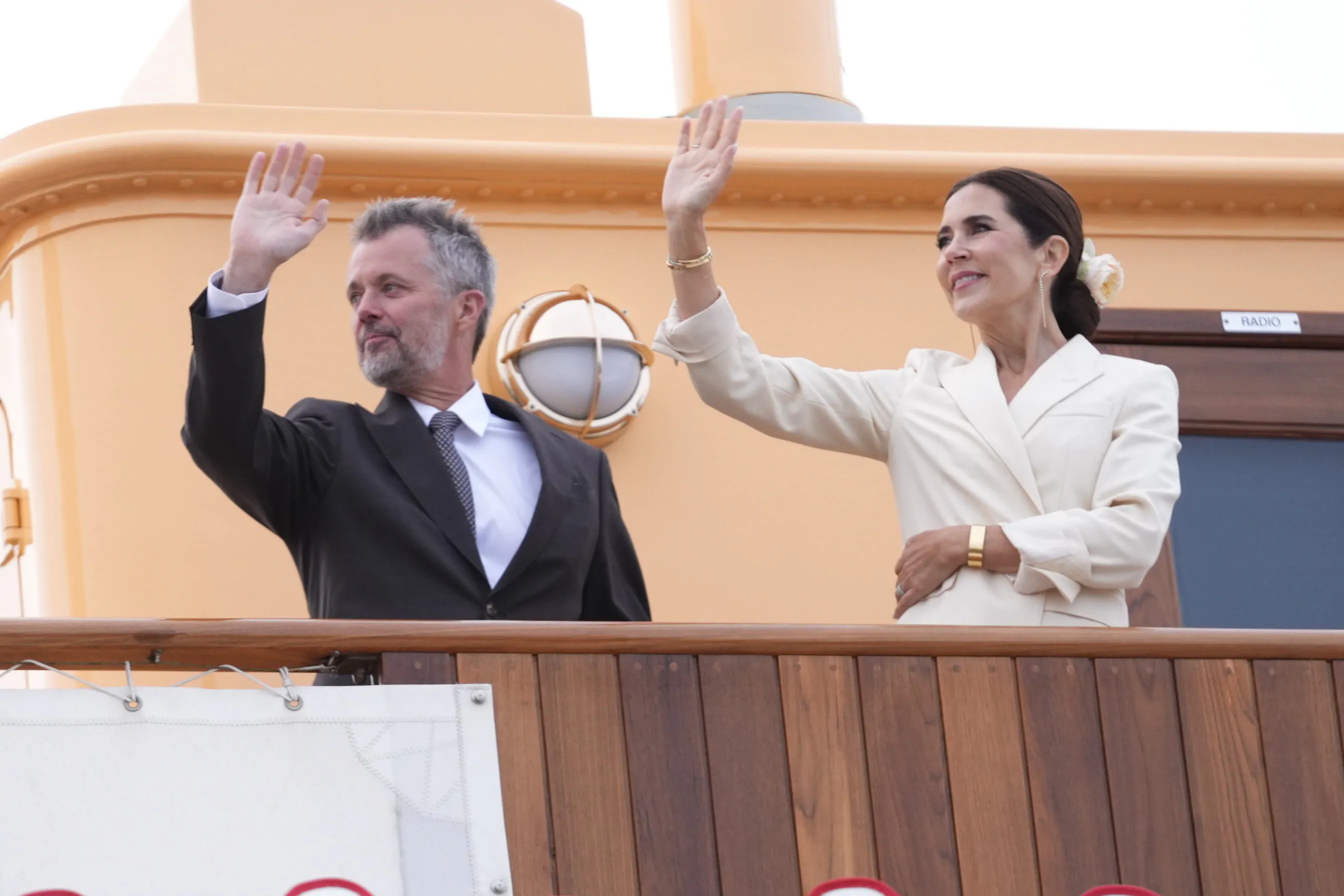 En glad og rørt kong Frederik vinker sammen med dronning Mary fra Kongeskibet Dannebrog.