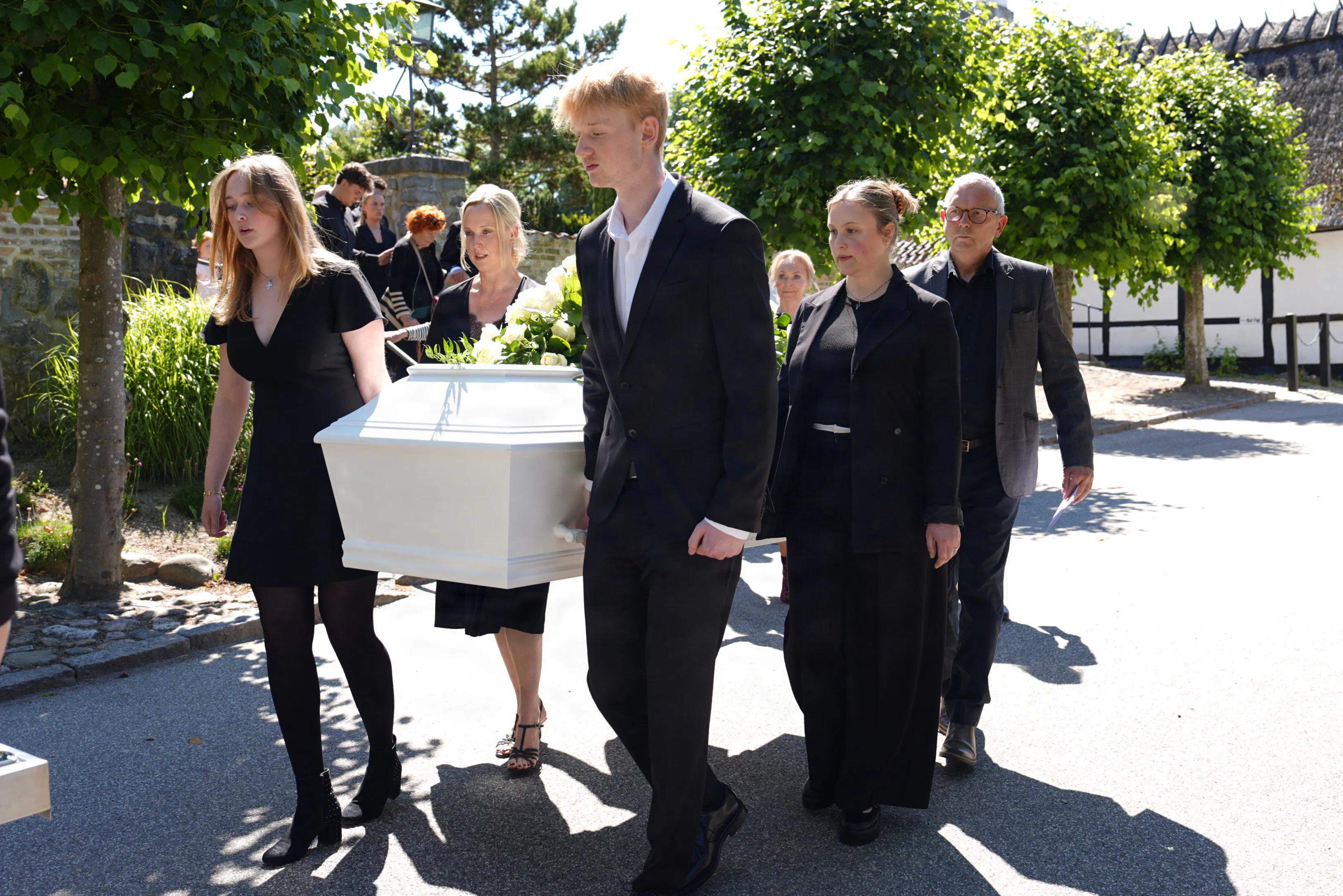 Børn og børnebørn bærer kisten ud til rustvognen.