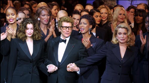 Yves Saint Laurent til sin afskedsopvisning, der samtidig markerede lukningen af Yves Saint Laurent som haute couture-hus. Her ses designeren med Laetitia Casta, Catherine Deneuve, Claudia Schiffer og Naomi Campbell alle klædt i Saint Laurent-suits.