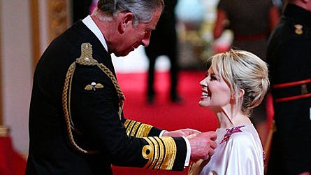 Den australske sangfugl Kylie Minogue storsmilede mens prins Charles påførte den britiske orden OBE.