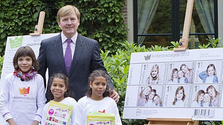 Kronprins Williem-Alexander fremviser de nye frimærker sammen med de tre udvalgte piger Daimy, Felicia and Fabienne, foran sit hus i Wassenaar.