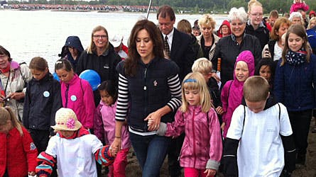 Kronprinsesse Mary hånd i hånd med to børn og omgivet af et mylder af andre ved dagens begivenhed på Juelsminde Strand.
