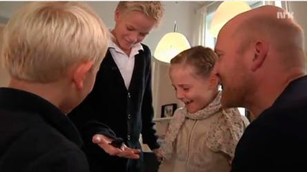 Marius holder en flagermus, mens hans søskende prinsesse Ingrid Alexandra og prins Sverre Magnus kigger på.